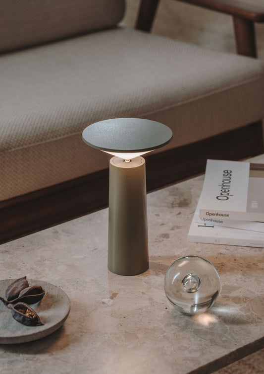 Lámpara portátil Cocktail gris oliva en ambiente de salón sobre mesa de centro de mármol
