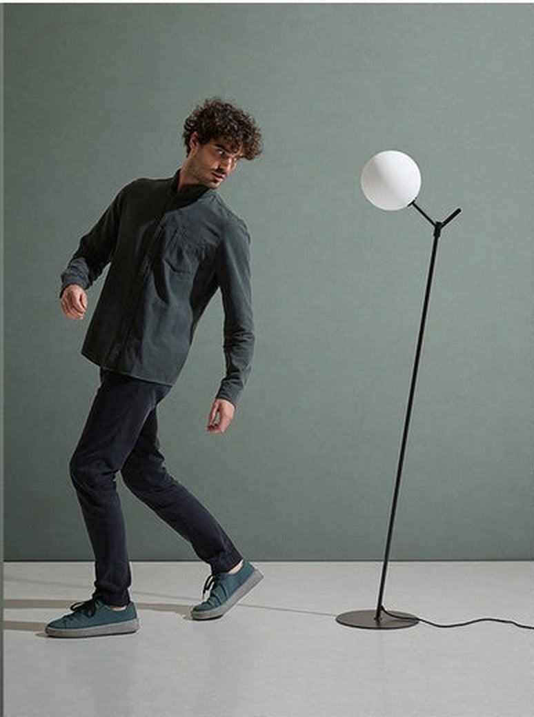 Lámpara de pie Atom en negro mate junto a una persona, referencia de escala de sus 155 cm de altura