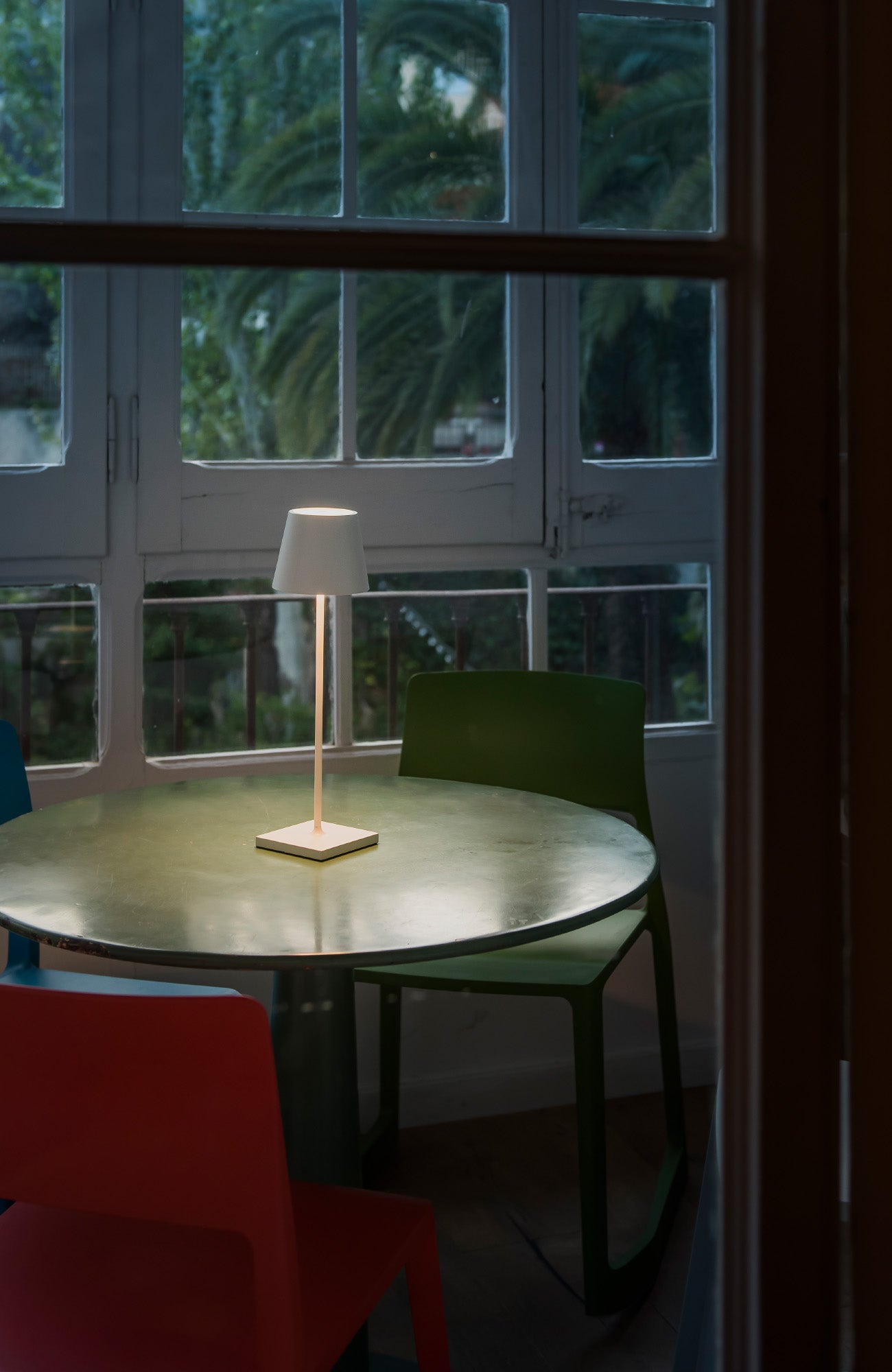 Lámpara portátil TOC encendida en mesa de cena exterior creando ambiente cálido